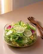 Salatschüssel aus Glas mit Salatbesteck und Untersetzer